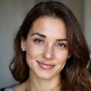 Porträt einer jungen Frau, die optimistisch in die Kamera blickt.